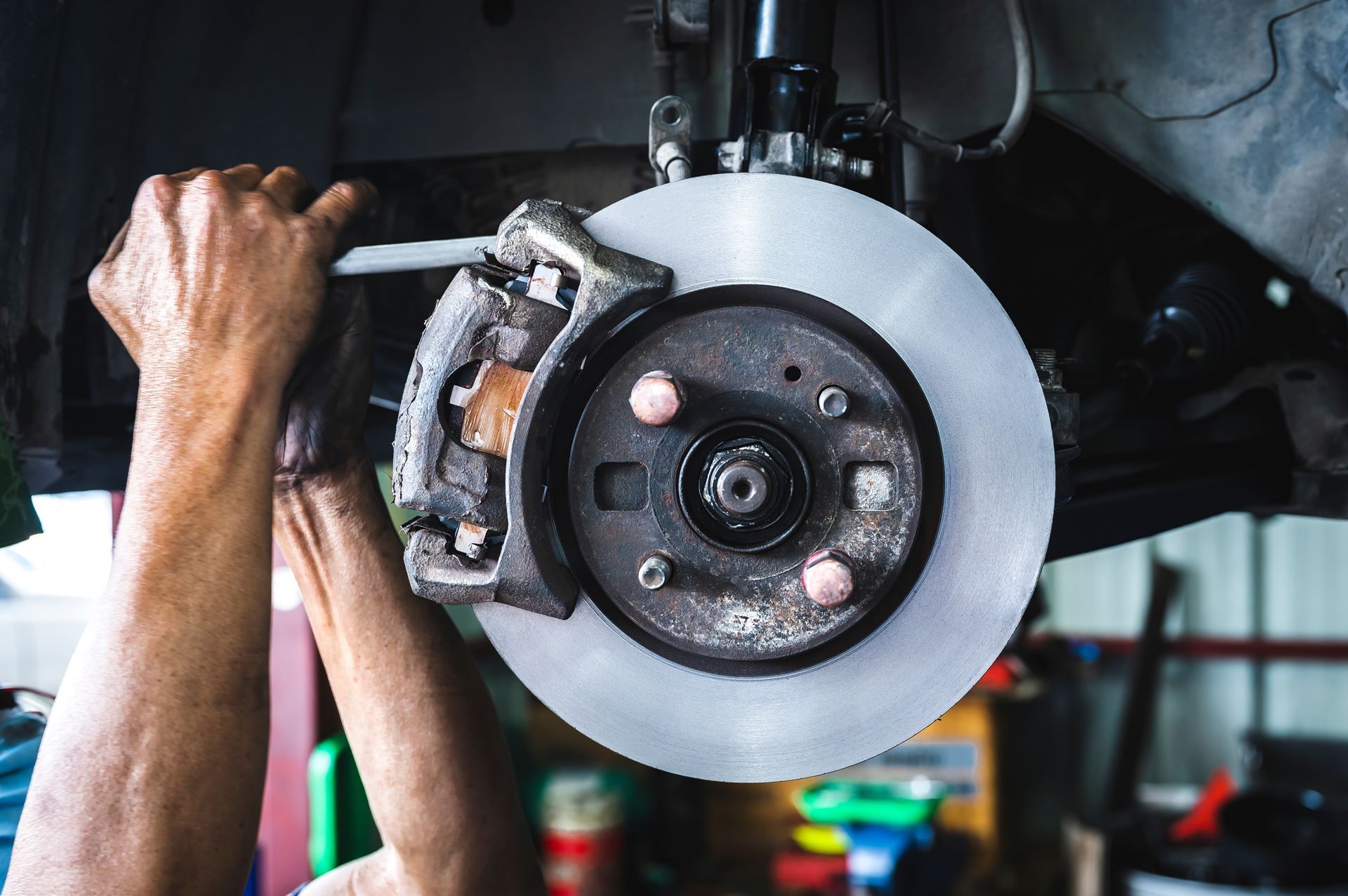 Hands working on a car brake rotor and caliper.