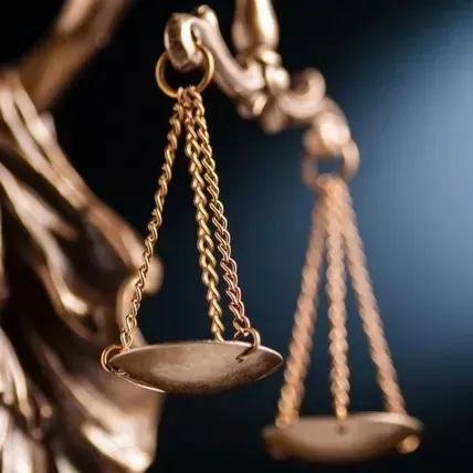 Scales of justice, gold, against a dark blue background with a spotlight.