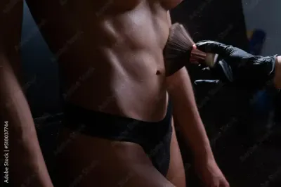 A woman is getting contouring done with her spray tan to make her abs appear more defined.