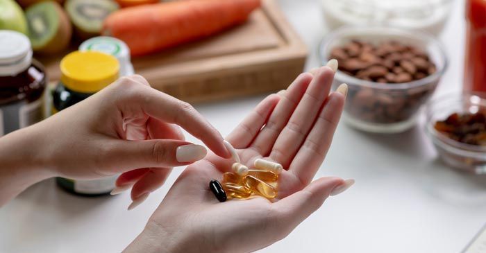 A woman is taking a pill from a bottle in her hand suggesting Nutritional Supplementation NY