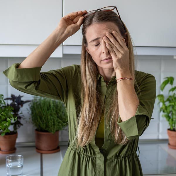 A woman in a green dress is tired covering her eyes with her hands suggesting Why Nutritional Supplementation Is a Cornerstone of True Health and Wellness. For Patients in Kingston Ulster County NY 12401
