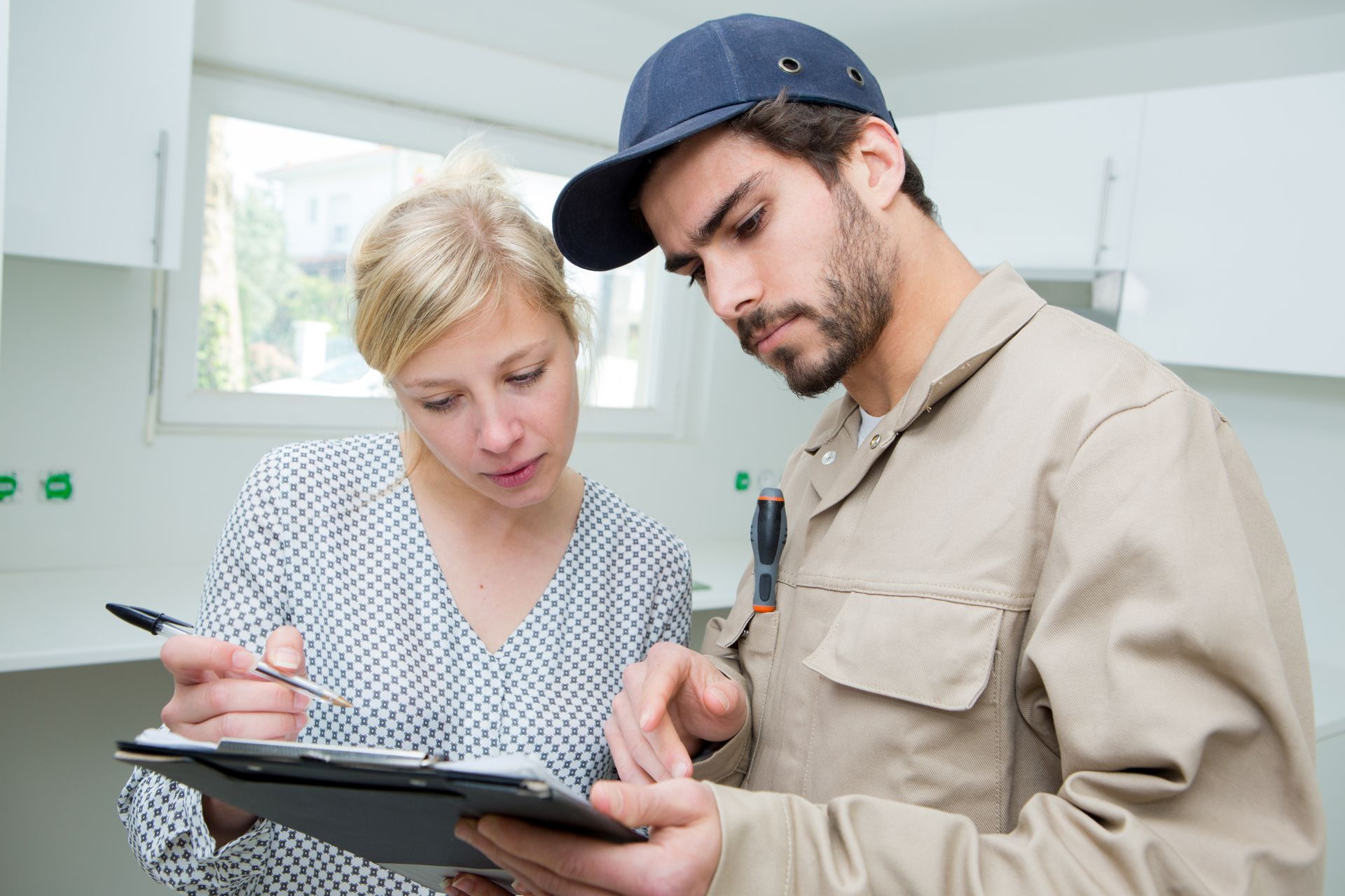 A plumber is asking for a customer’s signature after working in her kitchen. A plumber is asking for a customer’s signature after working in her kitchen.