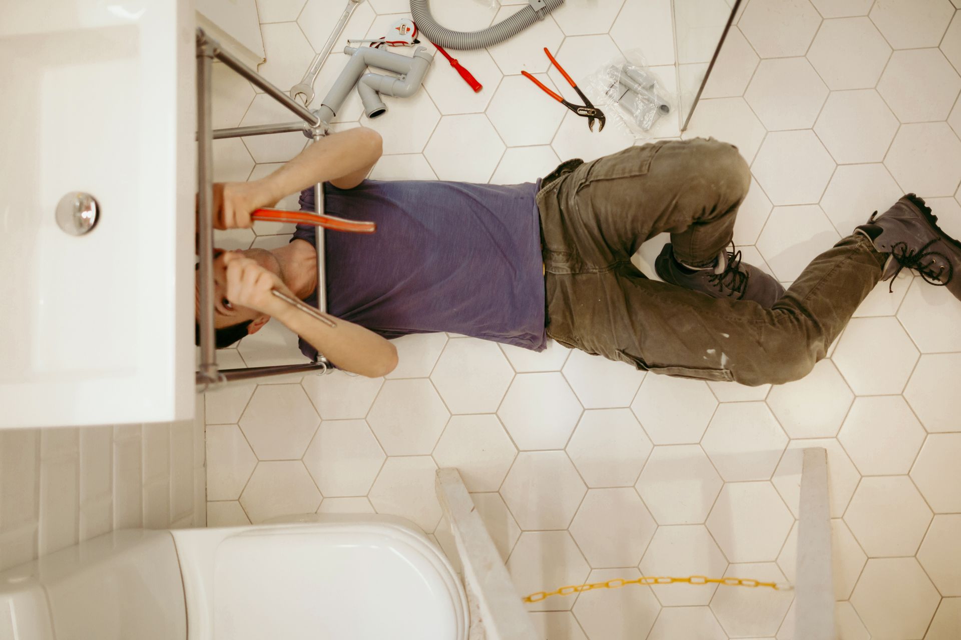 A person lying on the floor with his head on a sink | Plumbing in Inverness FL