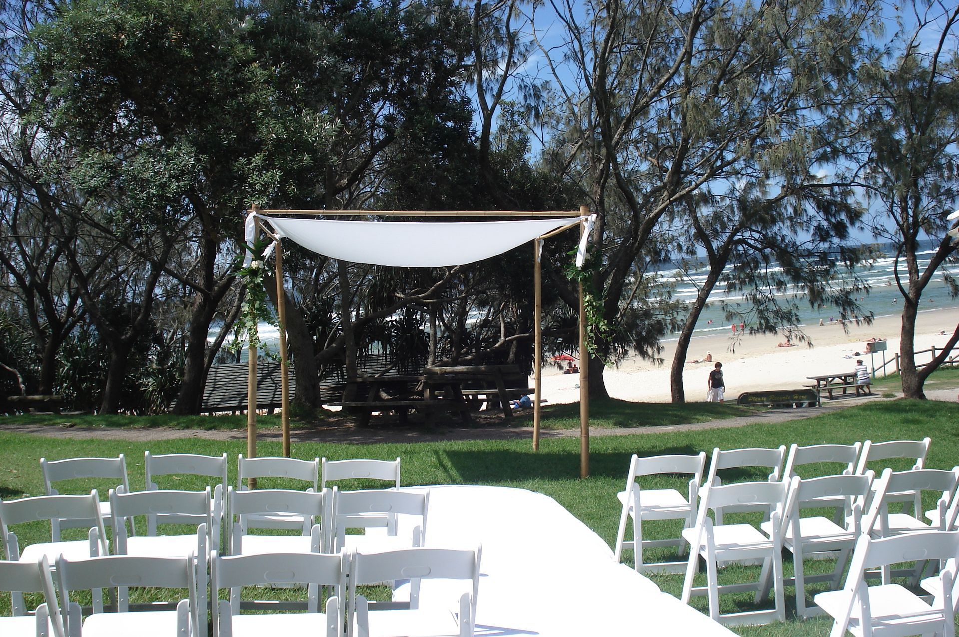 A row of white chairs in front of a canopy with a beach in the background