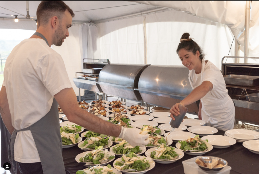 A man and a woman are preparing food in a tent.