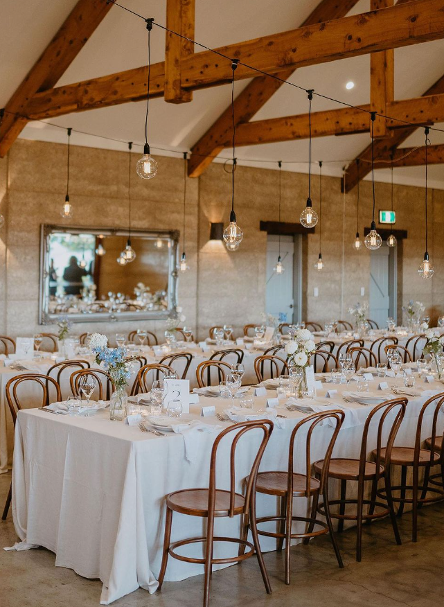 A large room with tables and chairs set up for a wedding reception.