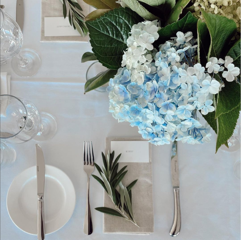 A table setting with blue flowers and silverware including a place card