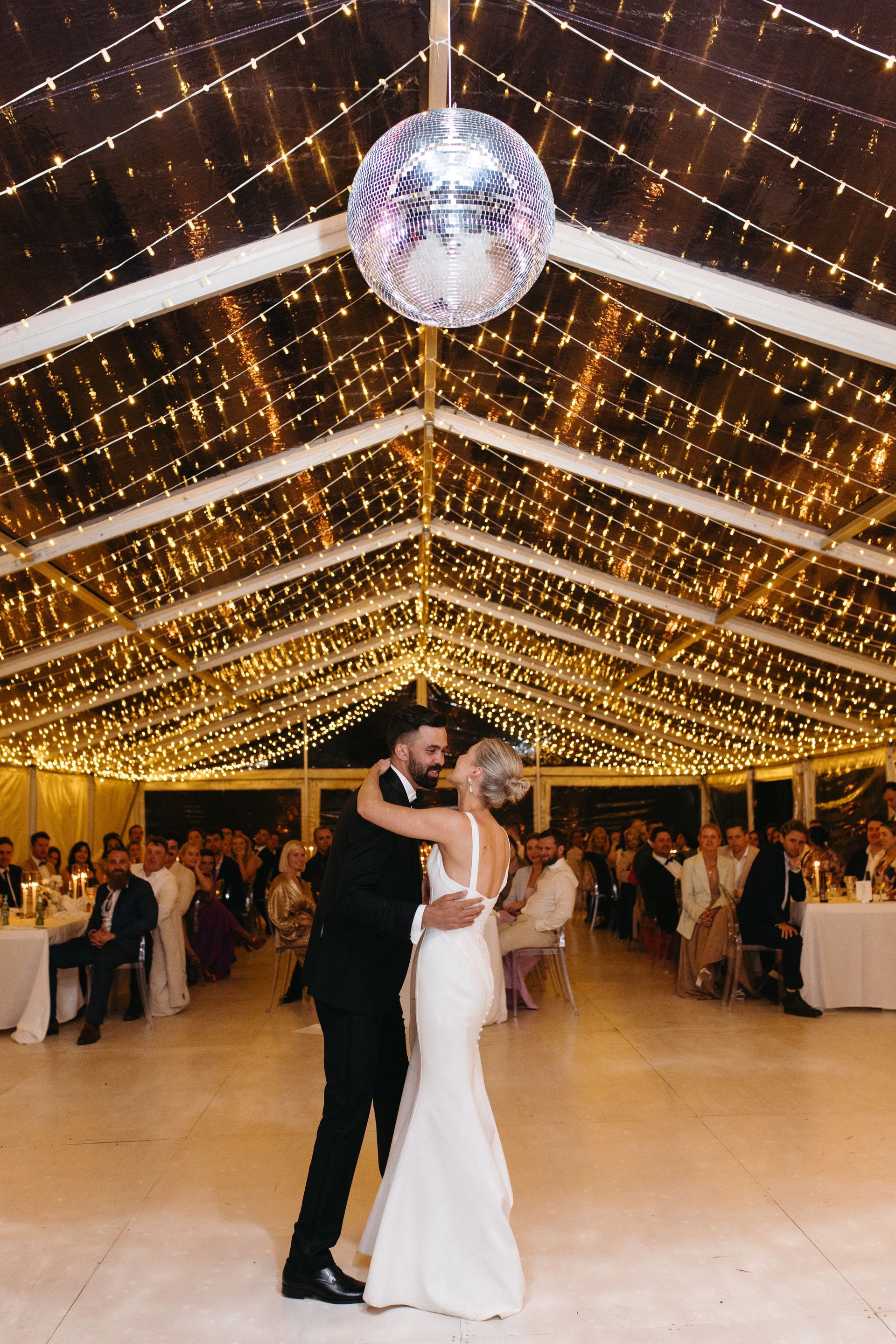 A bride and groom are dancing under a disco ball at their wedding reception.