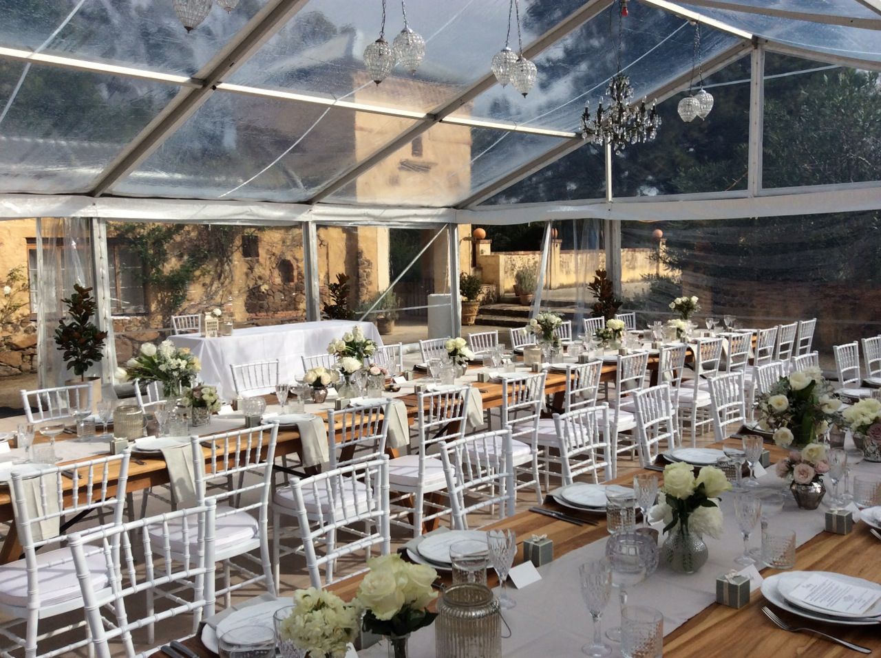 A large tent with tables and chairs set up for a wedding reception.