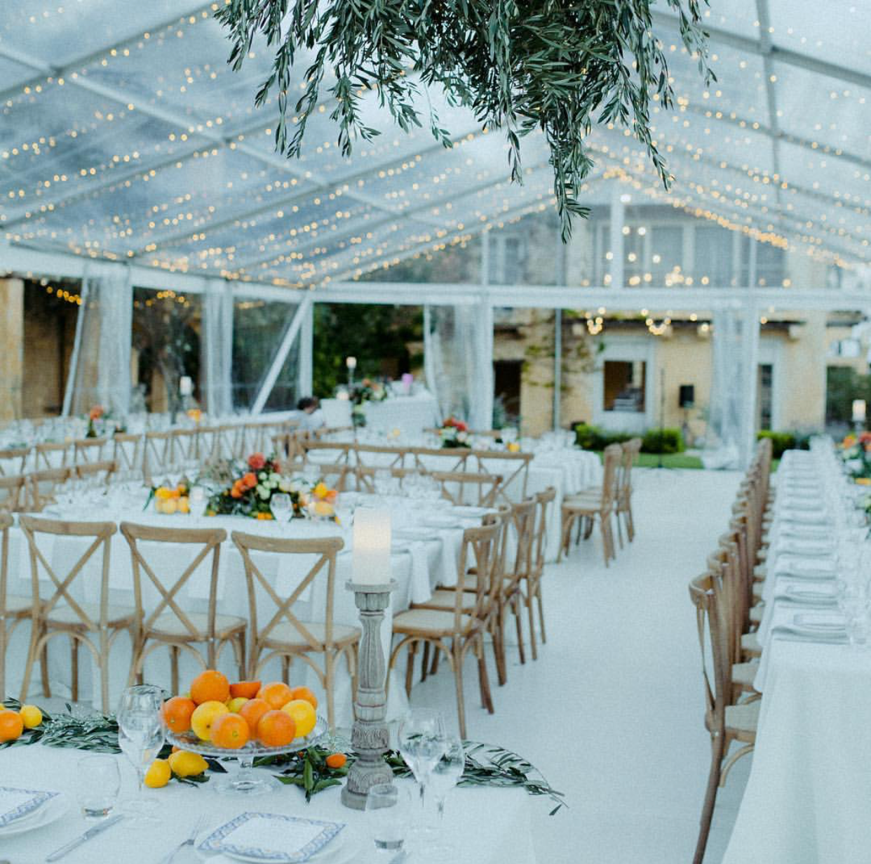 A large tent with tables and chairs set up for a wedding reception.