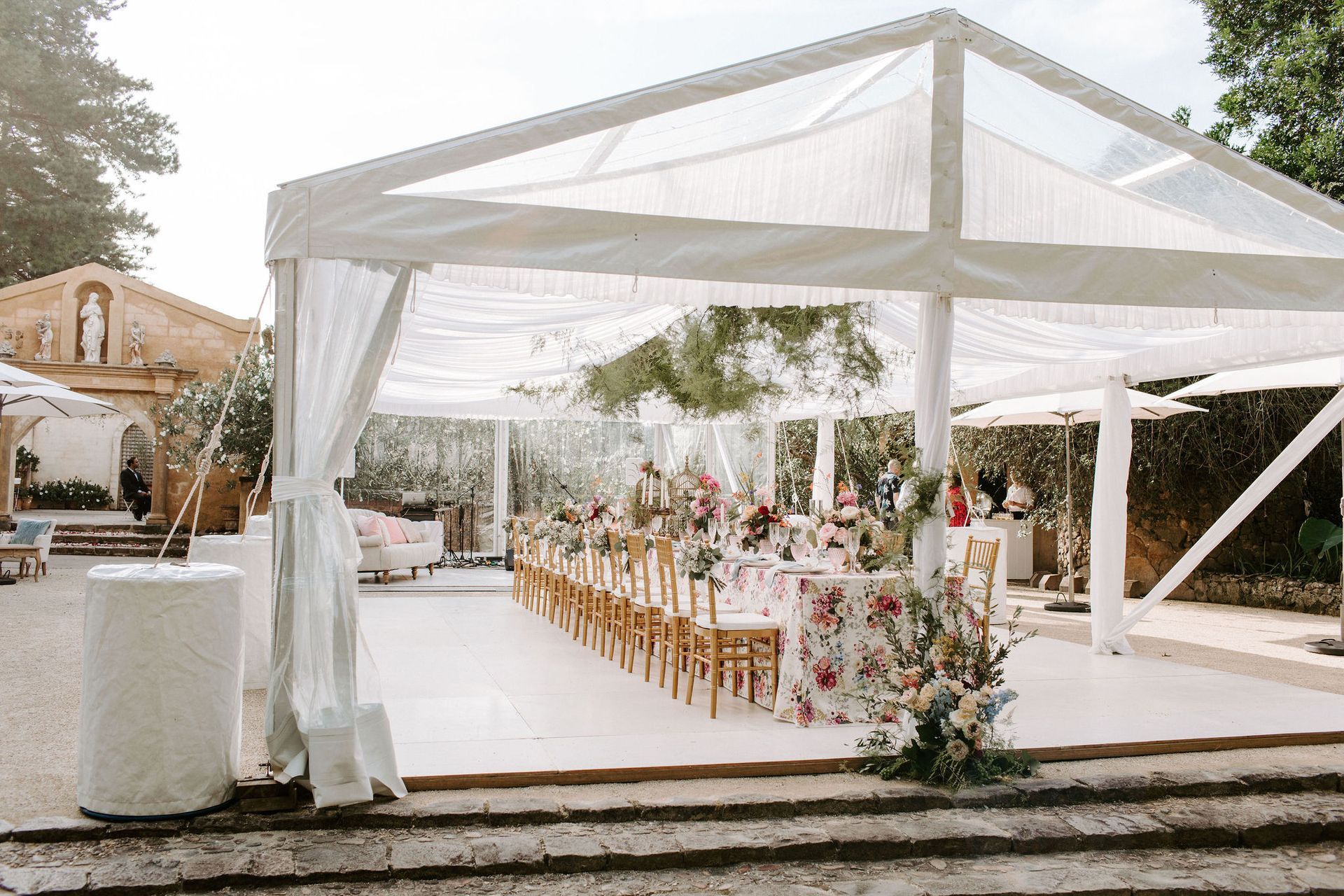 A long table and chairs under a clear tent.