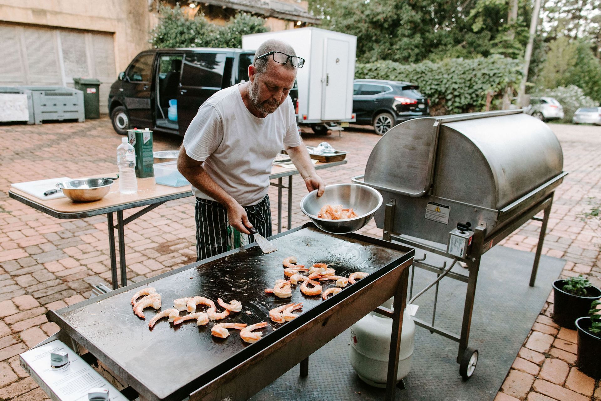 A man is cooking food on a grill outside.
