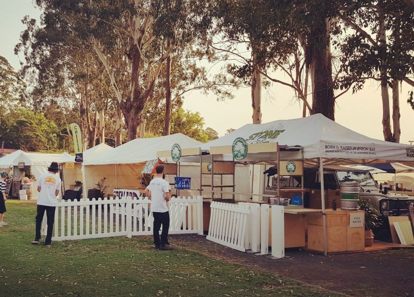A group of people standing in front of tents in a park.