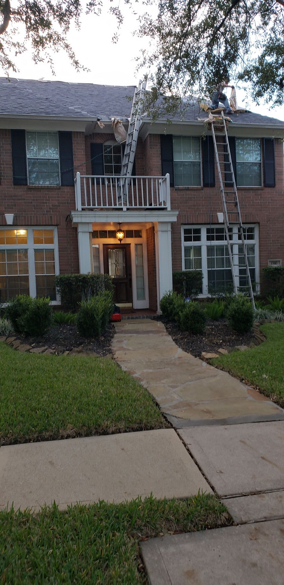A brick house with a balcony and a ladder on the roof.
