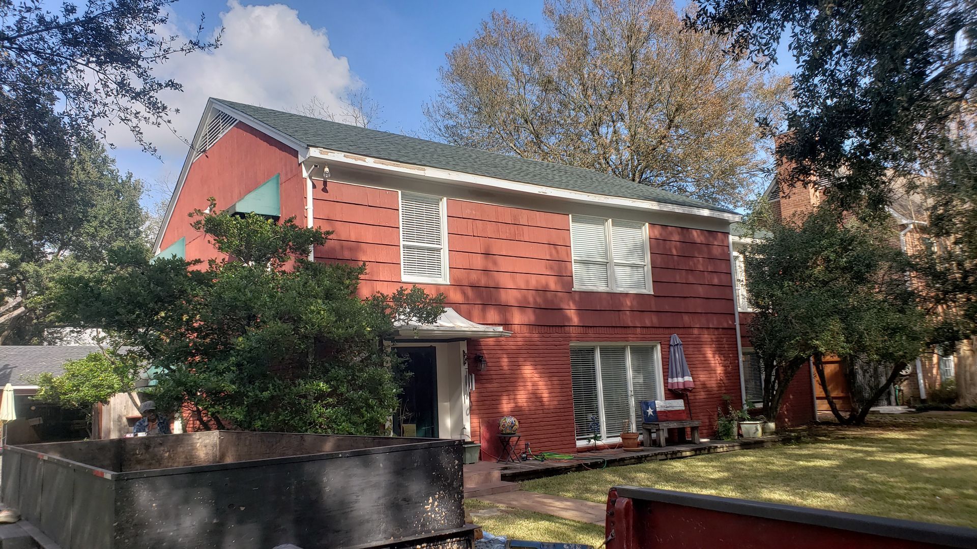A red house with a green roof and a truck parked in front of it.