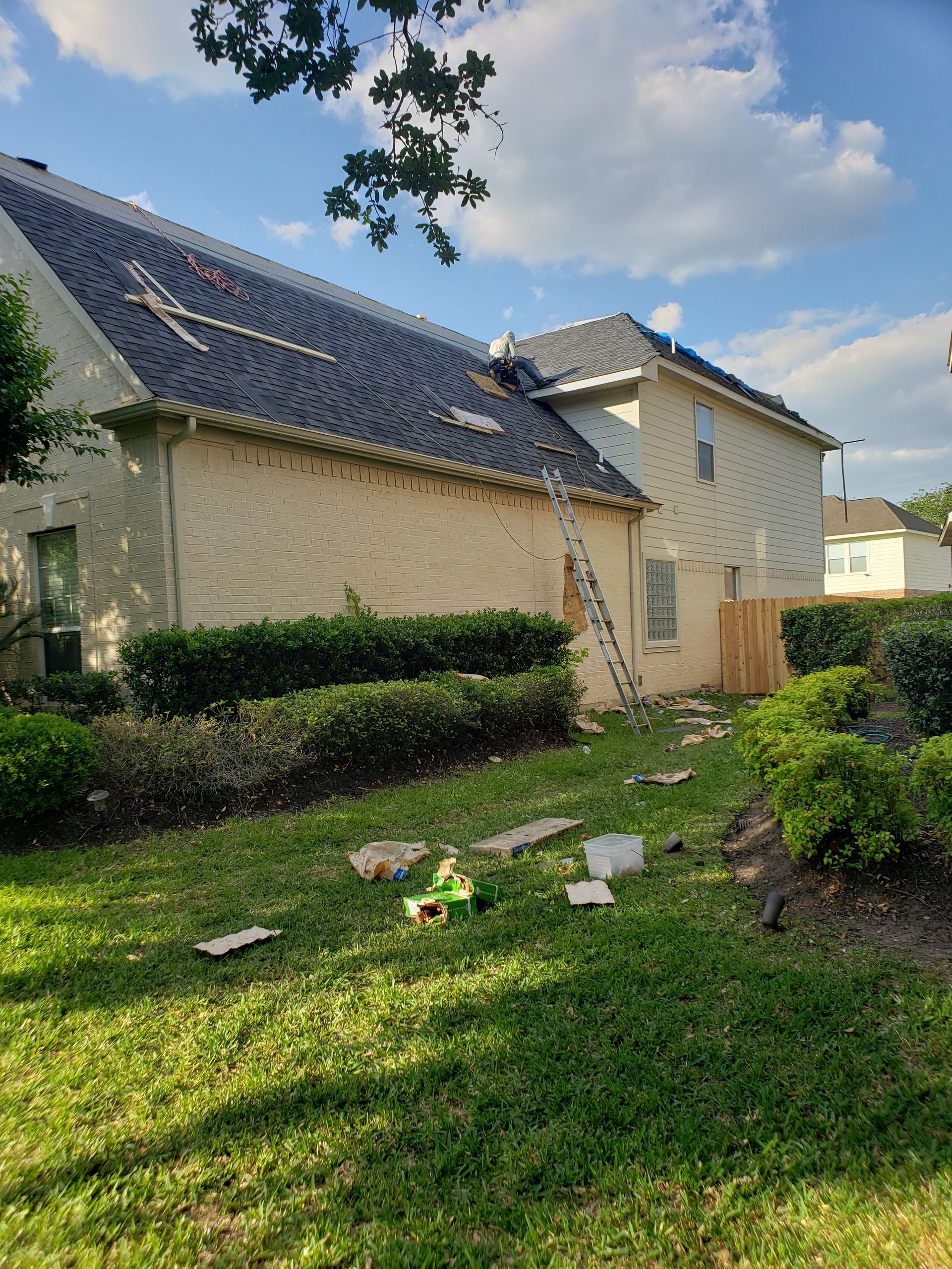 A house with a ladder in the backyard is being remodeled.