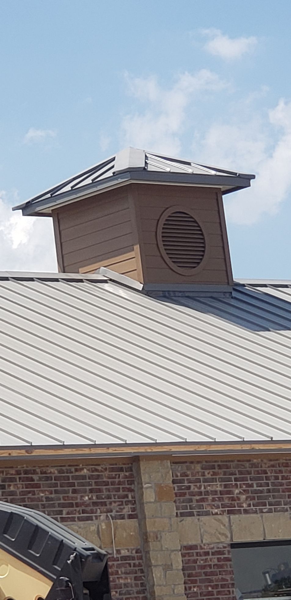 The roof of a building with a brick wall and a metal roof.