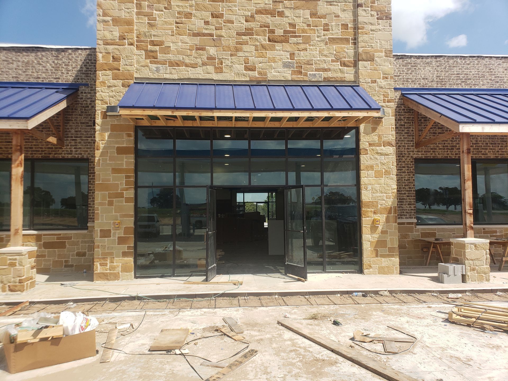 A brick building with a blue roof is under construction
