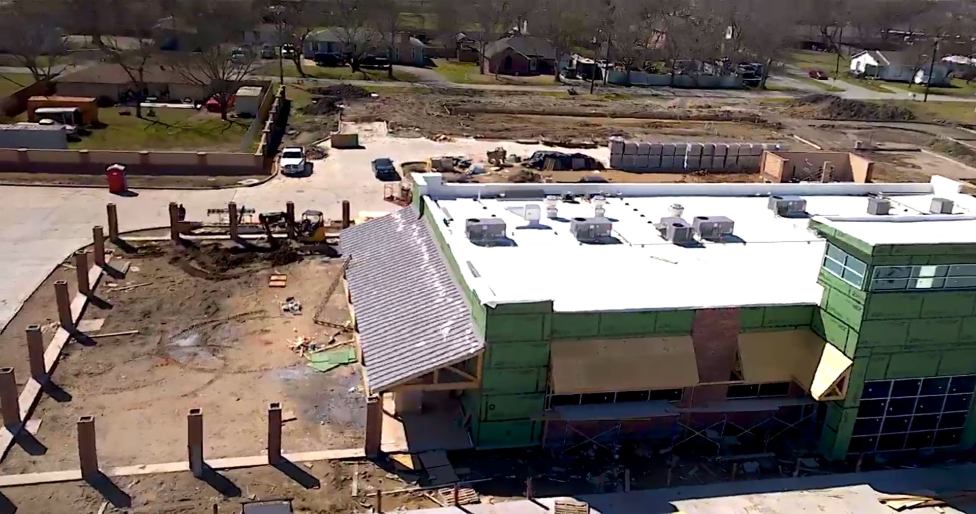 An aerial view of a building under construction with a white roof