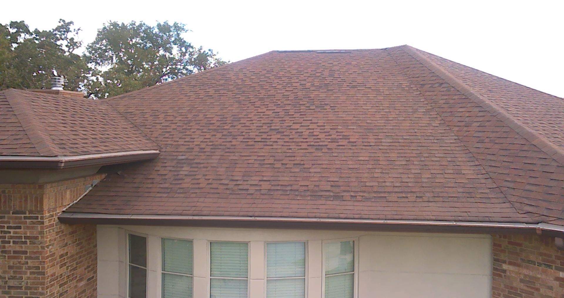 A brick house with a brown roof and a window.