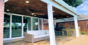 Patio with a white couch, sliding glass doors, and a wooden ceiling.
