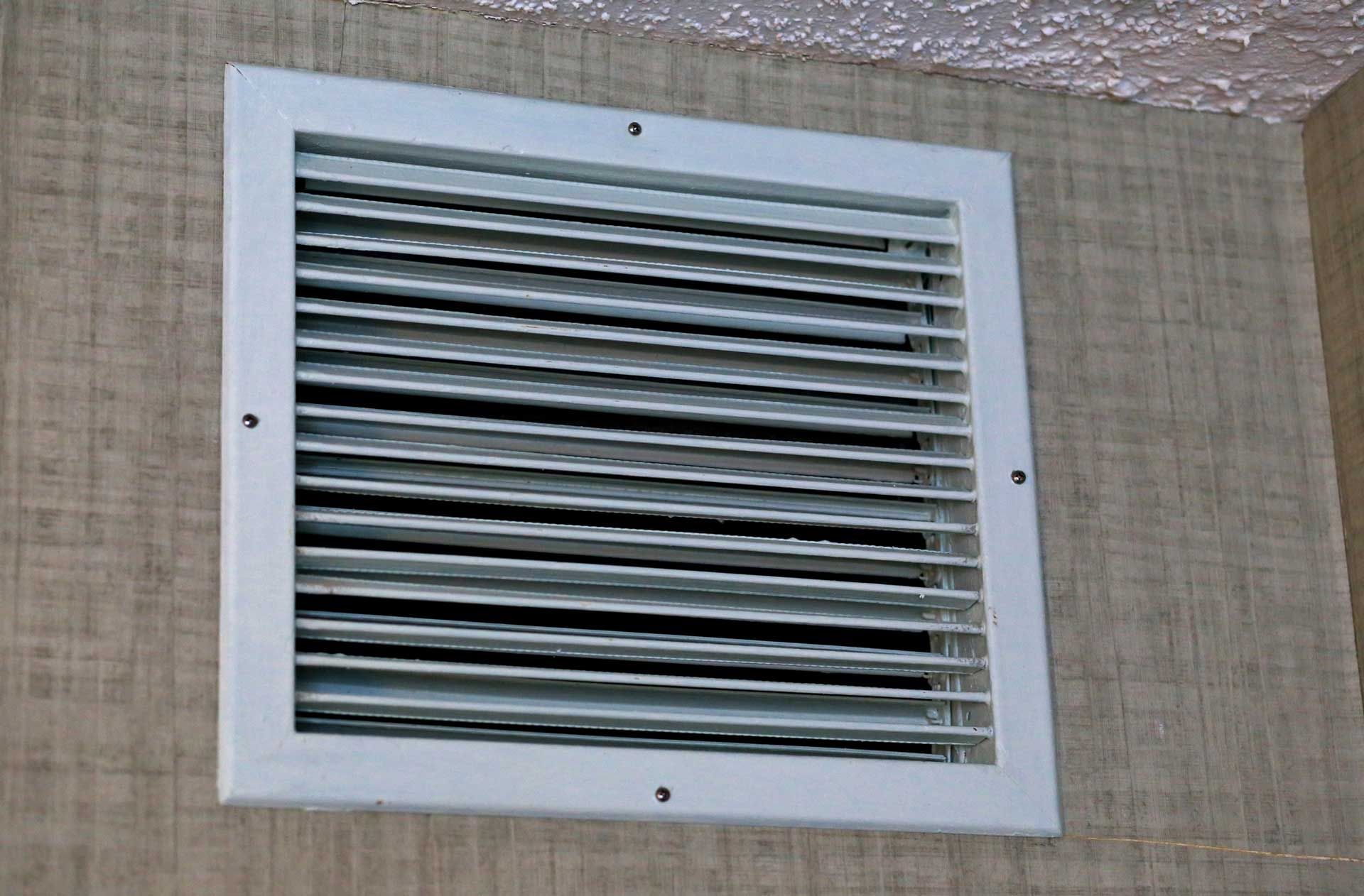 A white air vent is mounted to a wall.