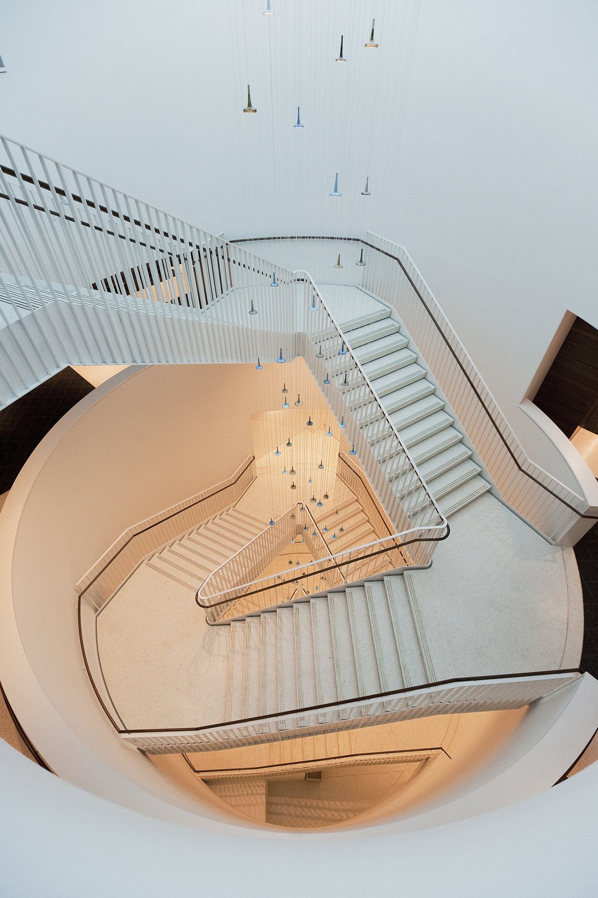 An aerial view of a spiral staircase with a chandelier hanging from the ceiling.
