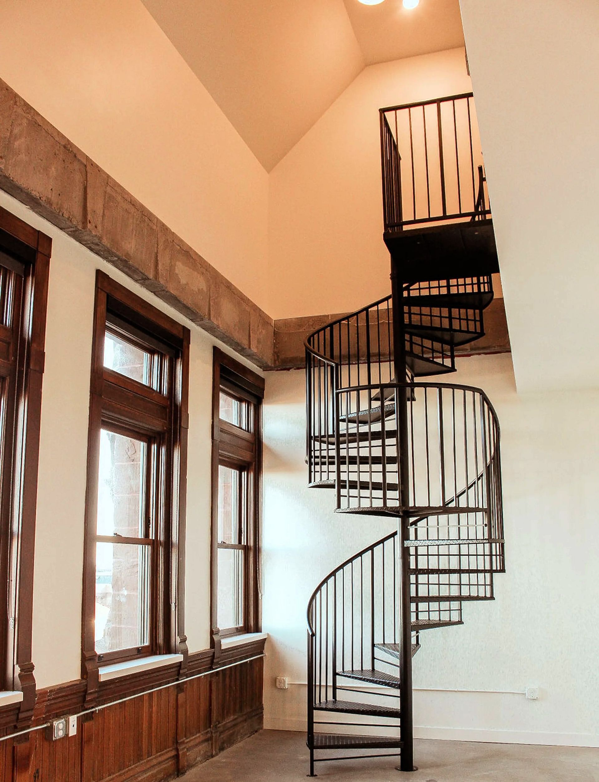 A spiral staircase in a room with lots of windows