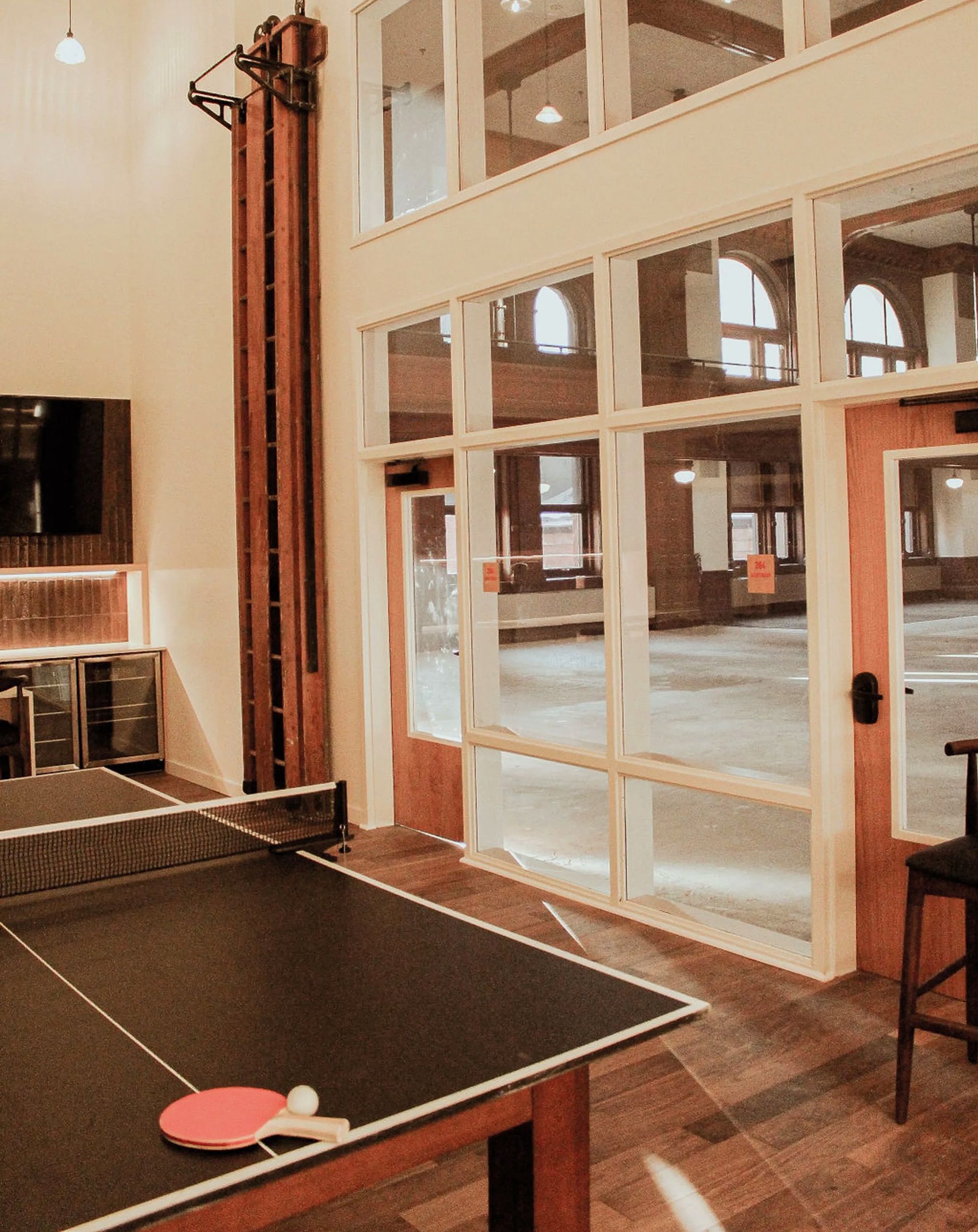 A ping pong table in a room with lots of windows