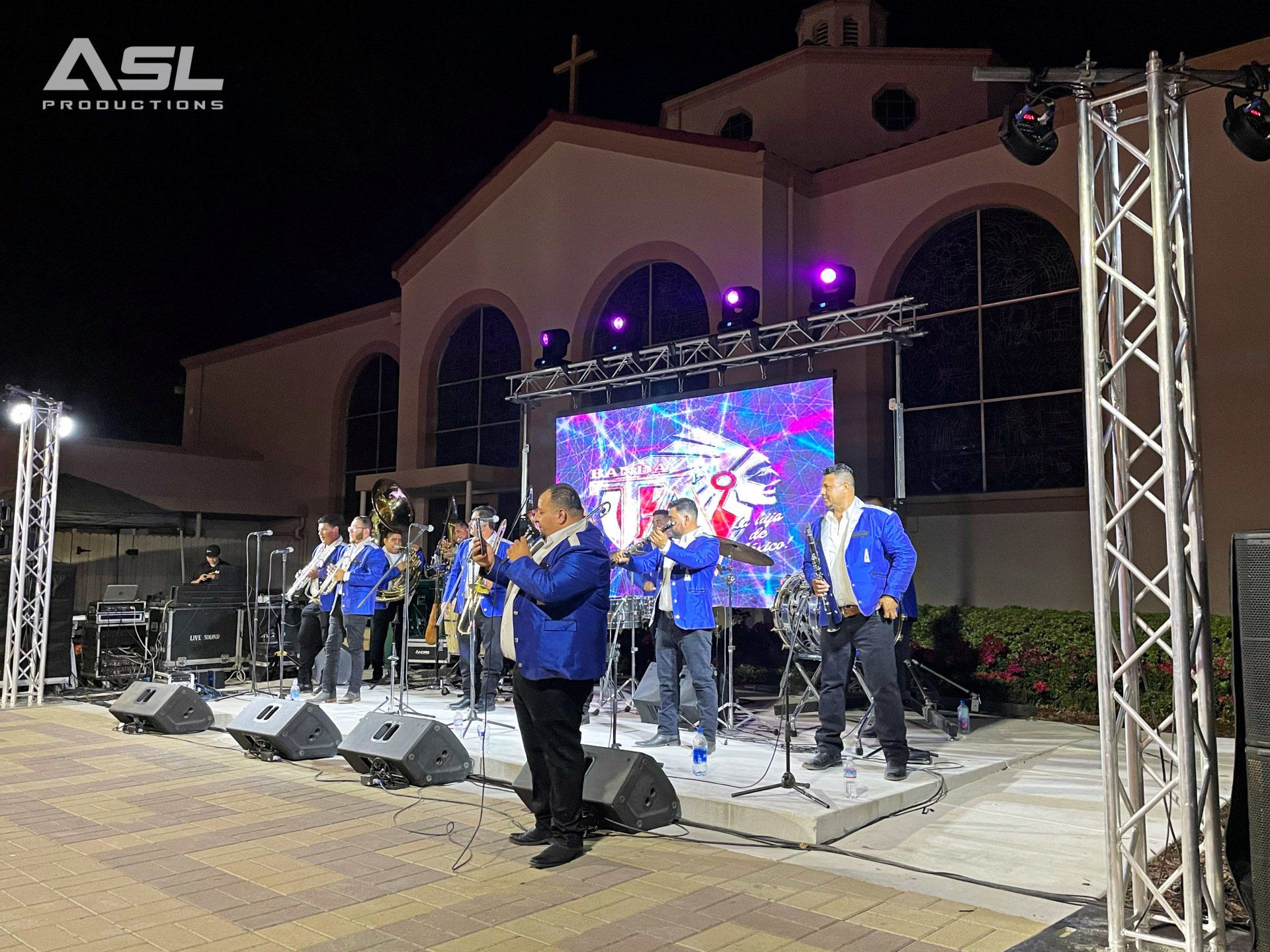 a band is playing on a stage in front of a large screen .
