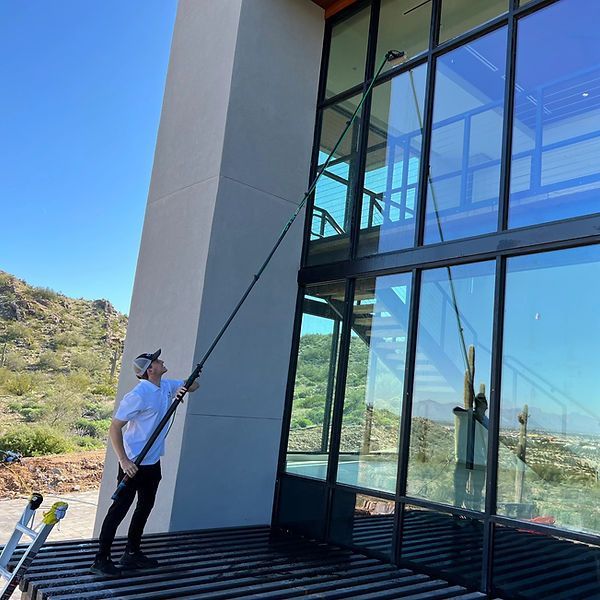 A man is cleaning the windows of a building with a ladder.