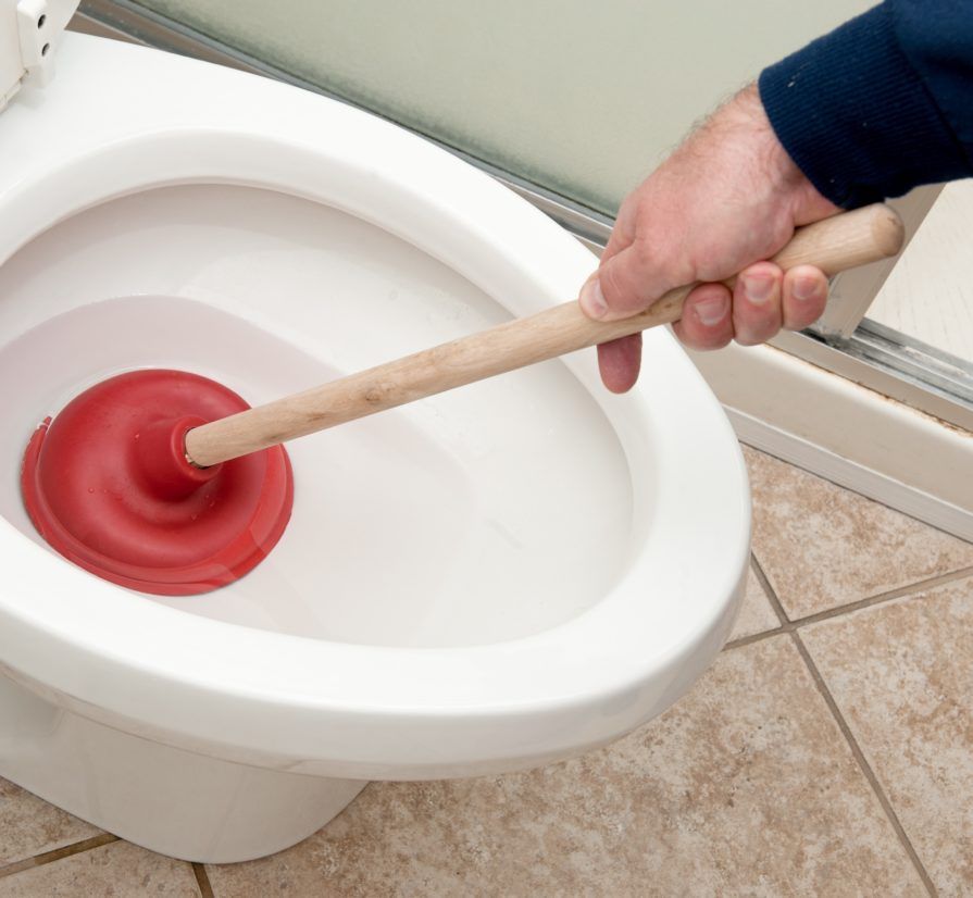 A person is using a plunger on a toilet