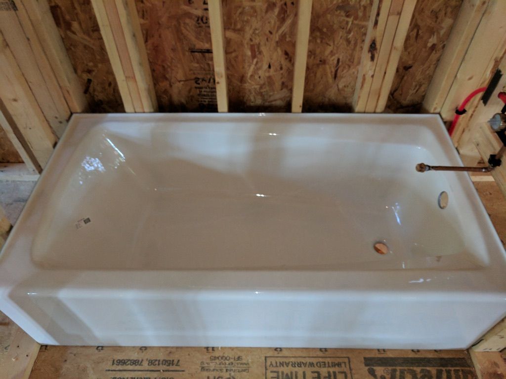 A white bathtub is sitting on top of a wooden wall.