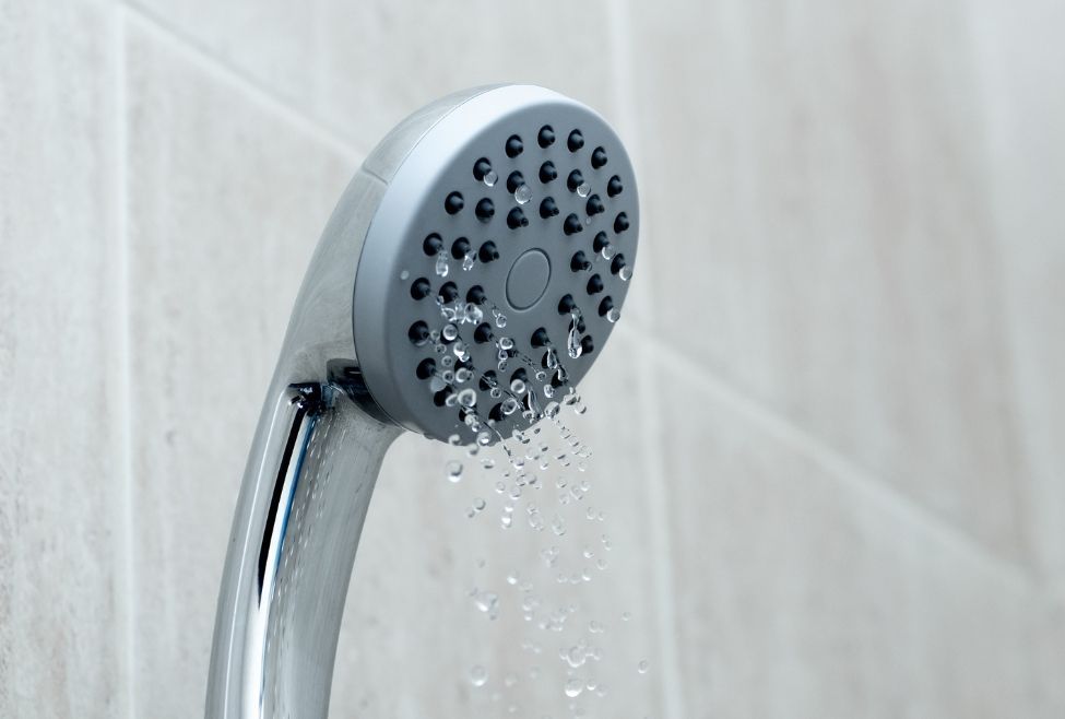 A close up of a shower head with water coming out of it.