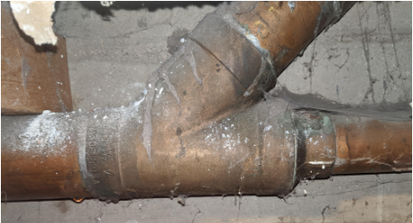 A close up of a copper pipe with water coming out of it.