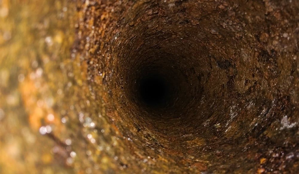 A close up of a rusty pipe with a hole in the middle.