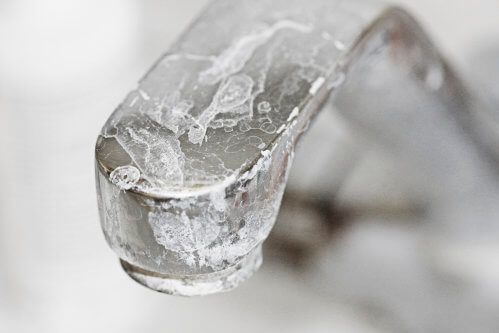 A close up of a faucet with a drop of water coming out of it.
