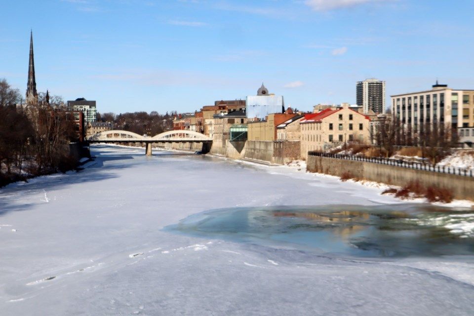 A frozen river in a city with a bridge in the background.
