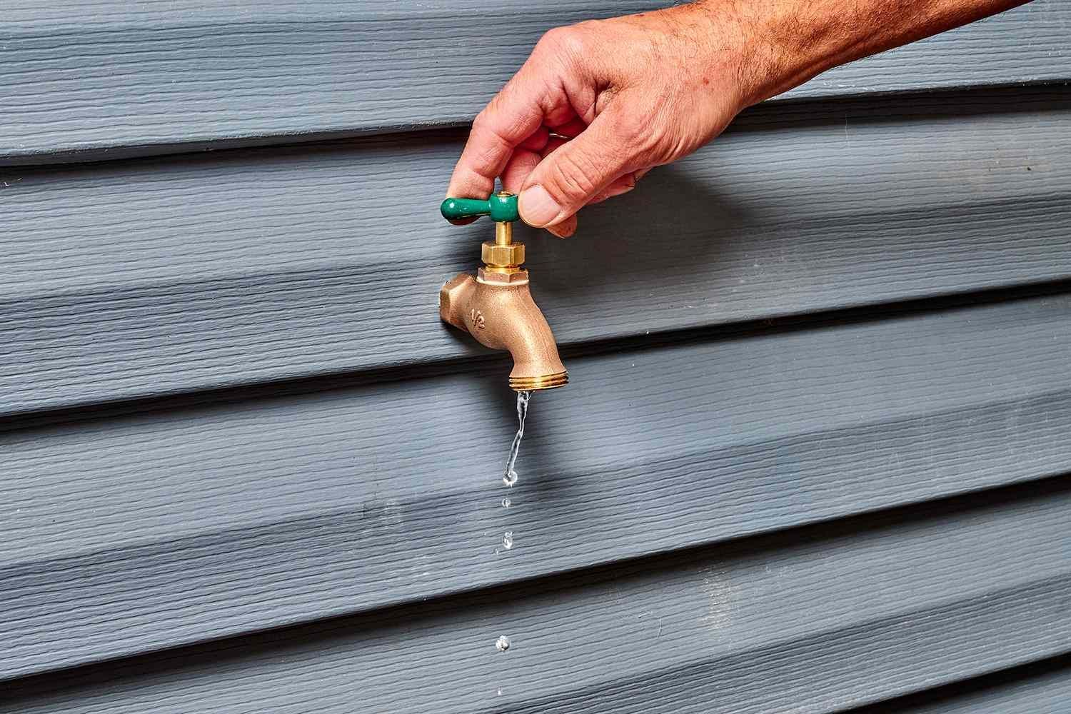 A person is turning on a faucet on a wall.