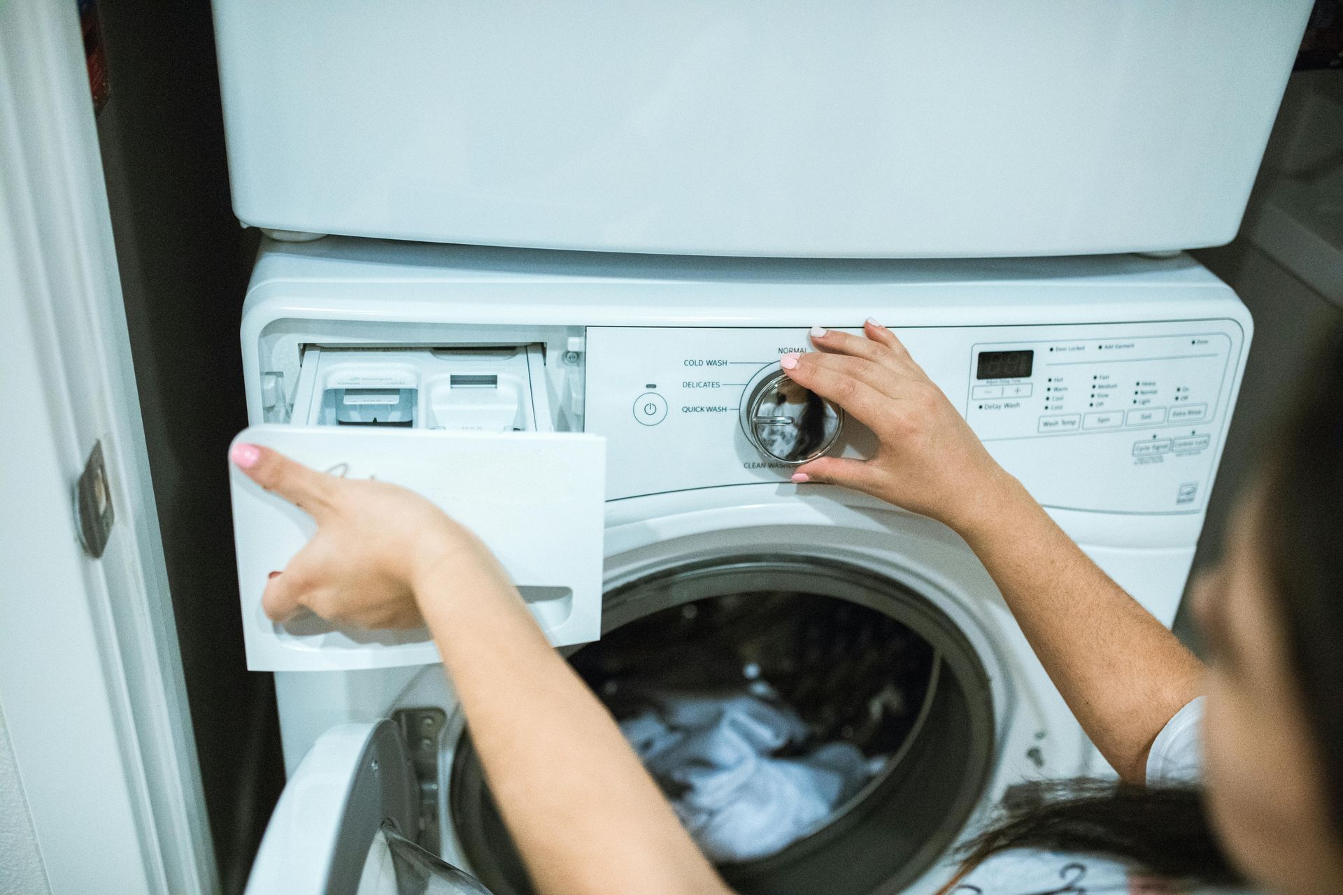 A woman is loading clothes into a washing machine.