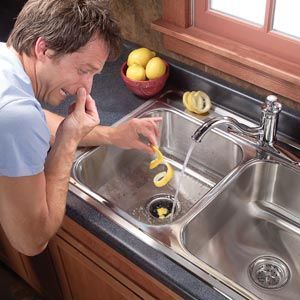 A man is peeling a lemon in a kitchen sink.