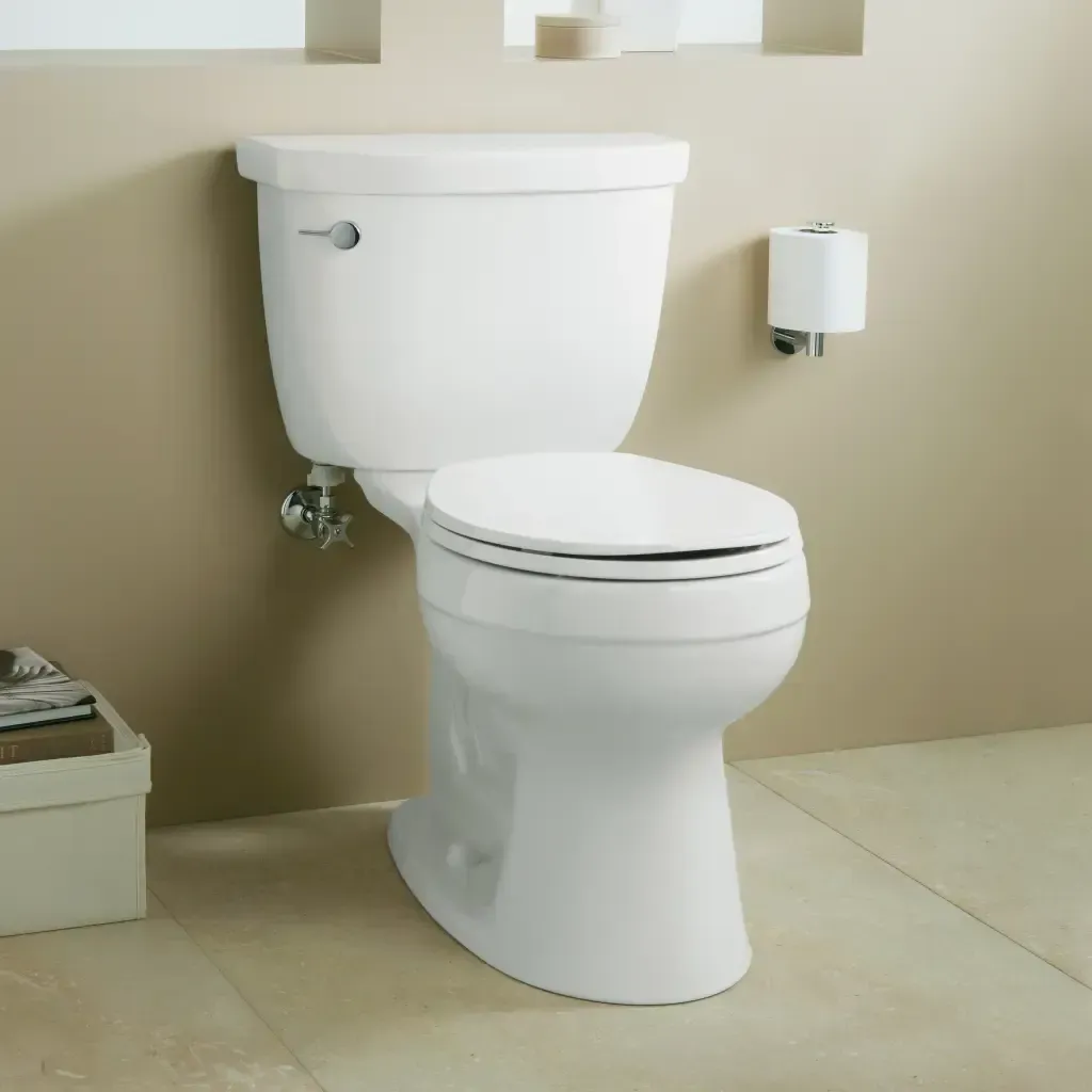 A white toilet in a bathroom next to a paper towel dispenser