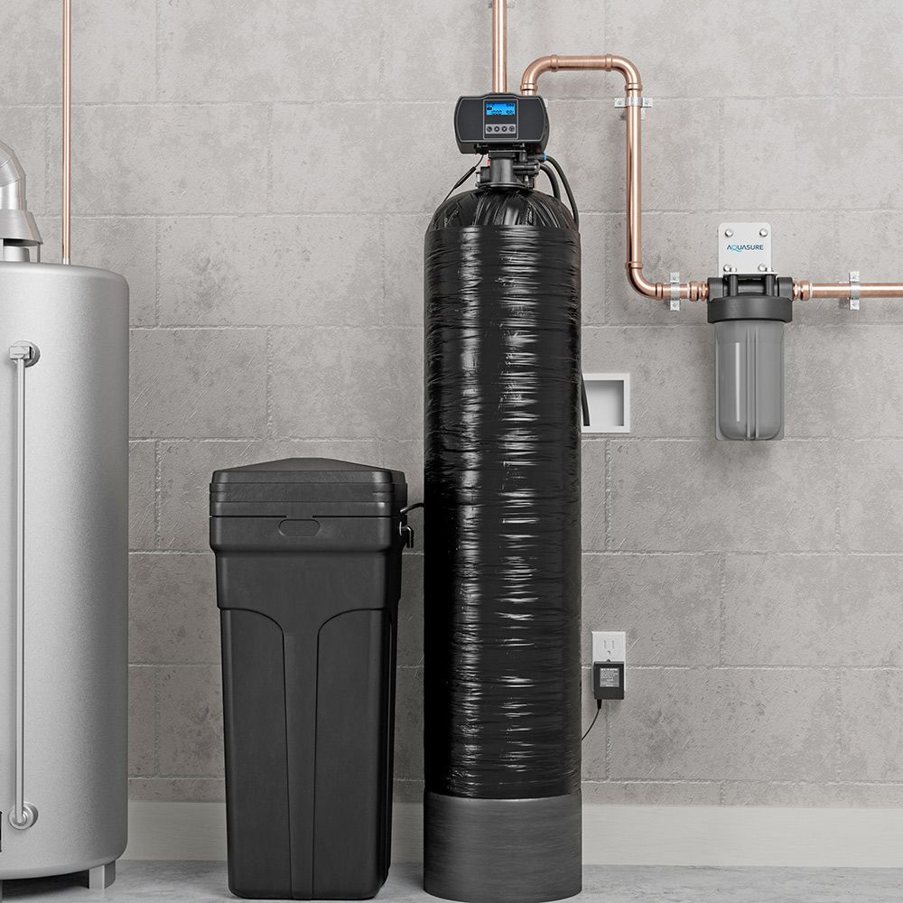 A water filter is sitting next to a water heater in a basement.