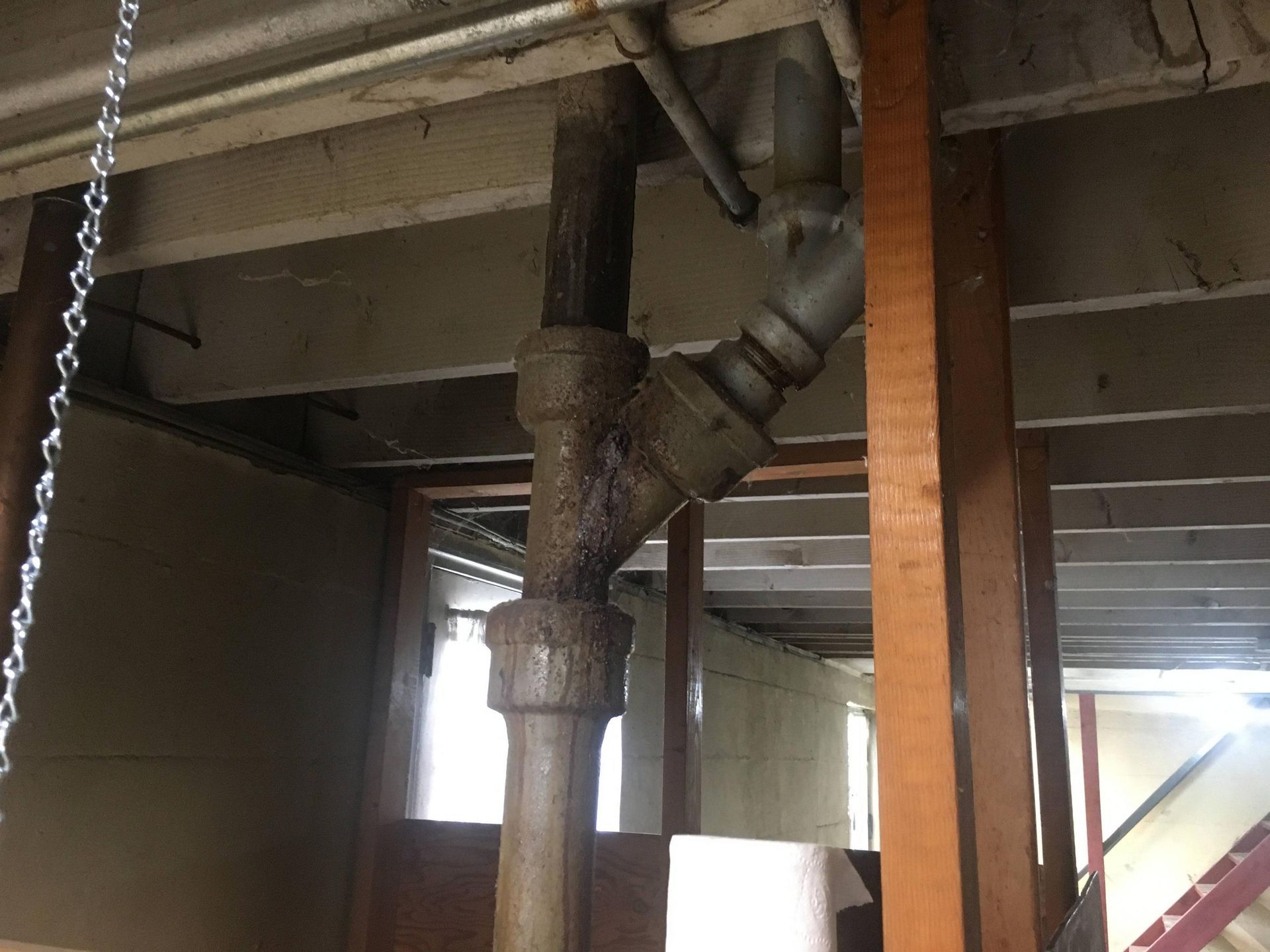 A pipe is hanging from the ceiling in a basement.