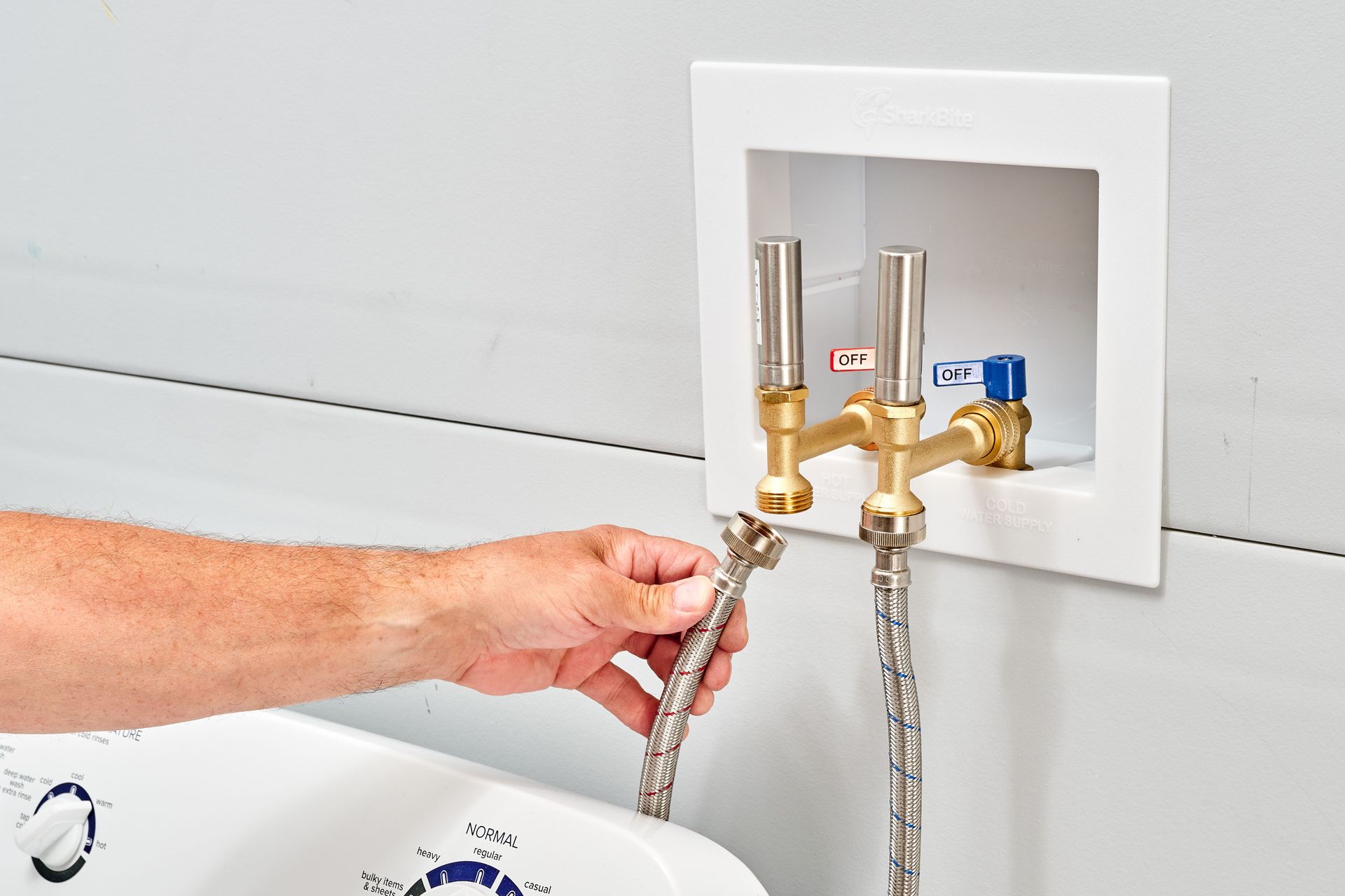 A person is connecting a hose to a faucet in a bathroom.