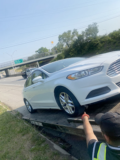 A white car is being towed by a tow truck.
