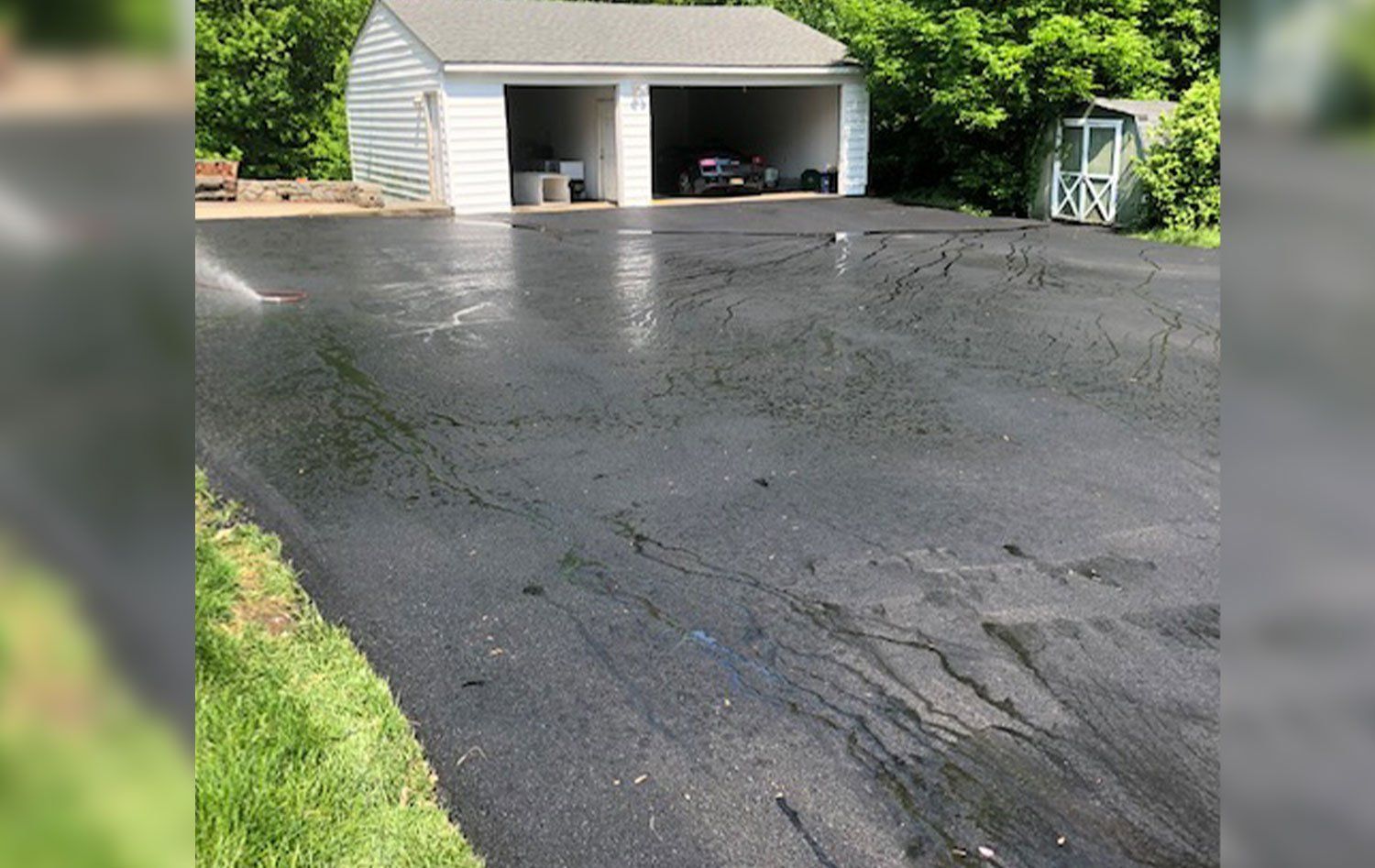 A driveway leading to a garage with two cars parked in it.