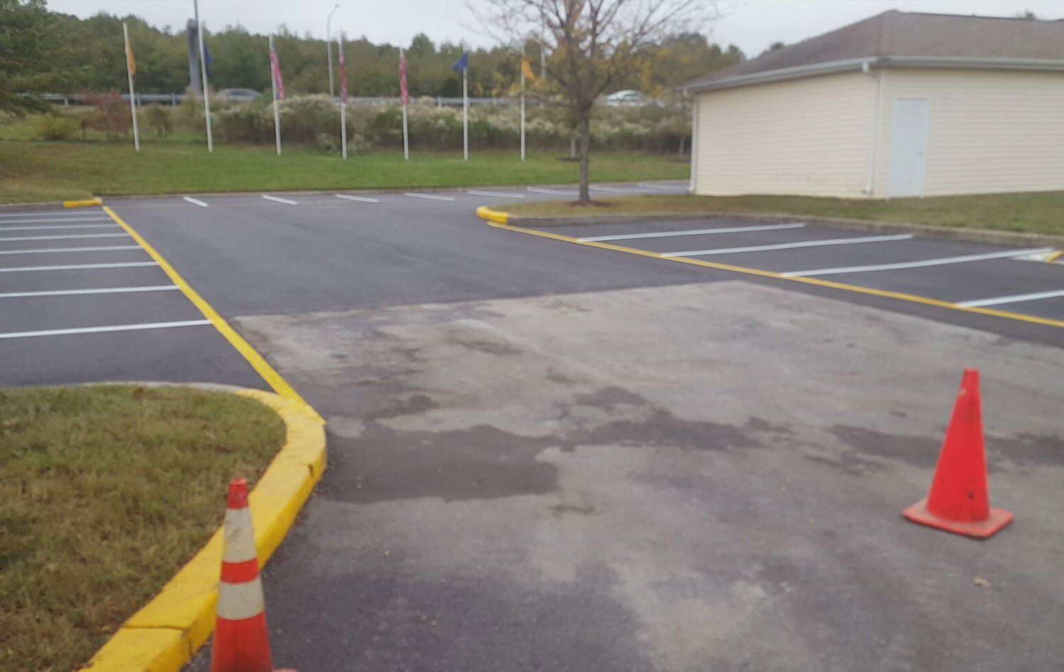 A parking lot with a yellow curb and a red cone
