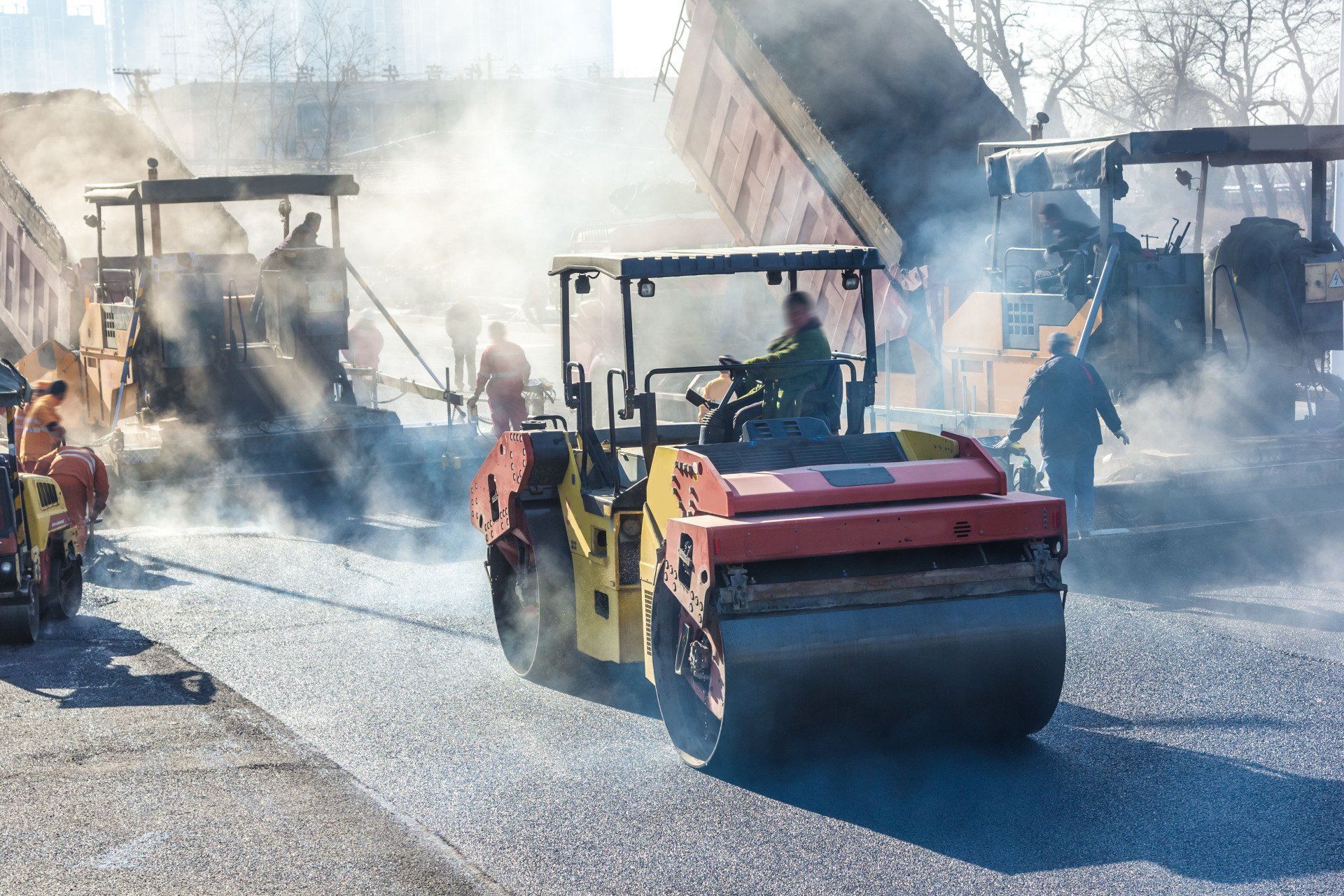 A group of construction vehicles are working on a road.