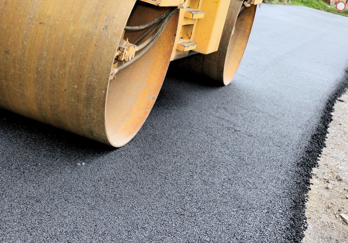 A yellow roller is rolling asphalt on a road.